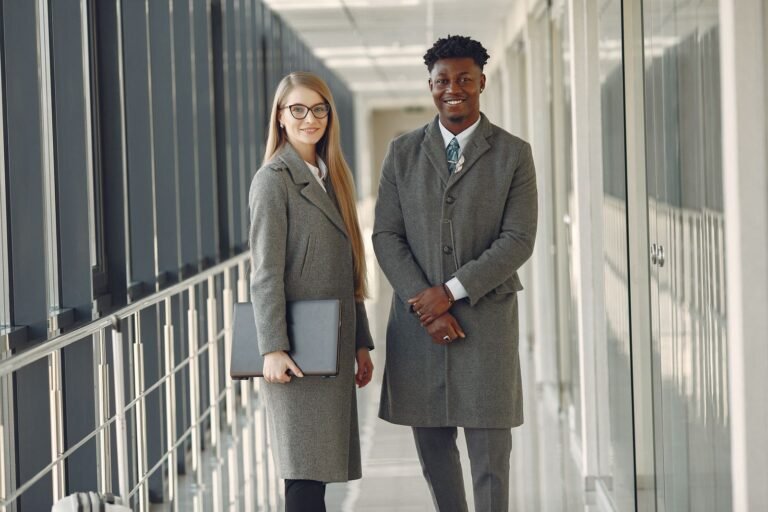 Confident business leaders standing in modern office hallway